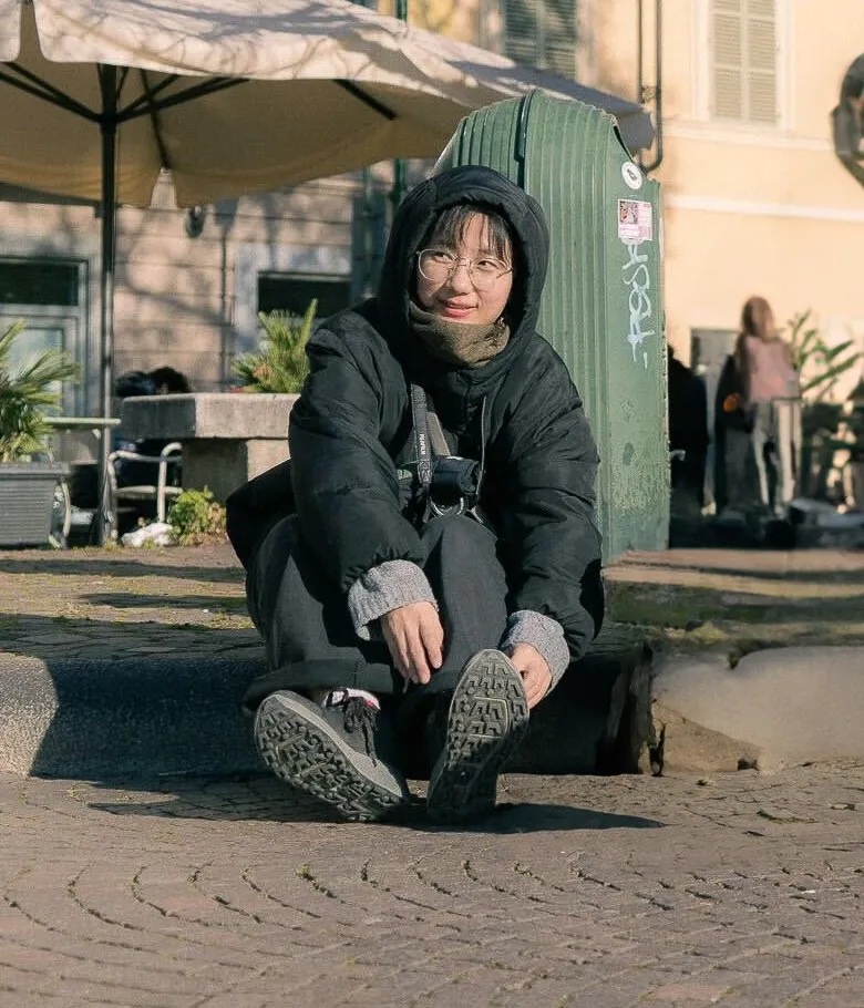 Yase Dusu sitting on a kerb in Torino, smiling