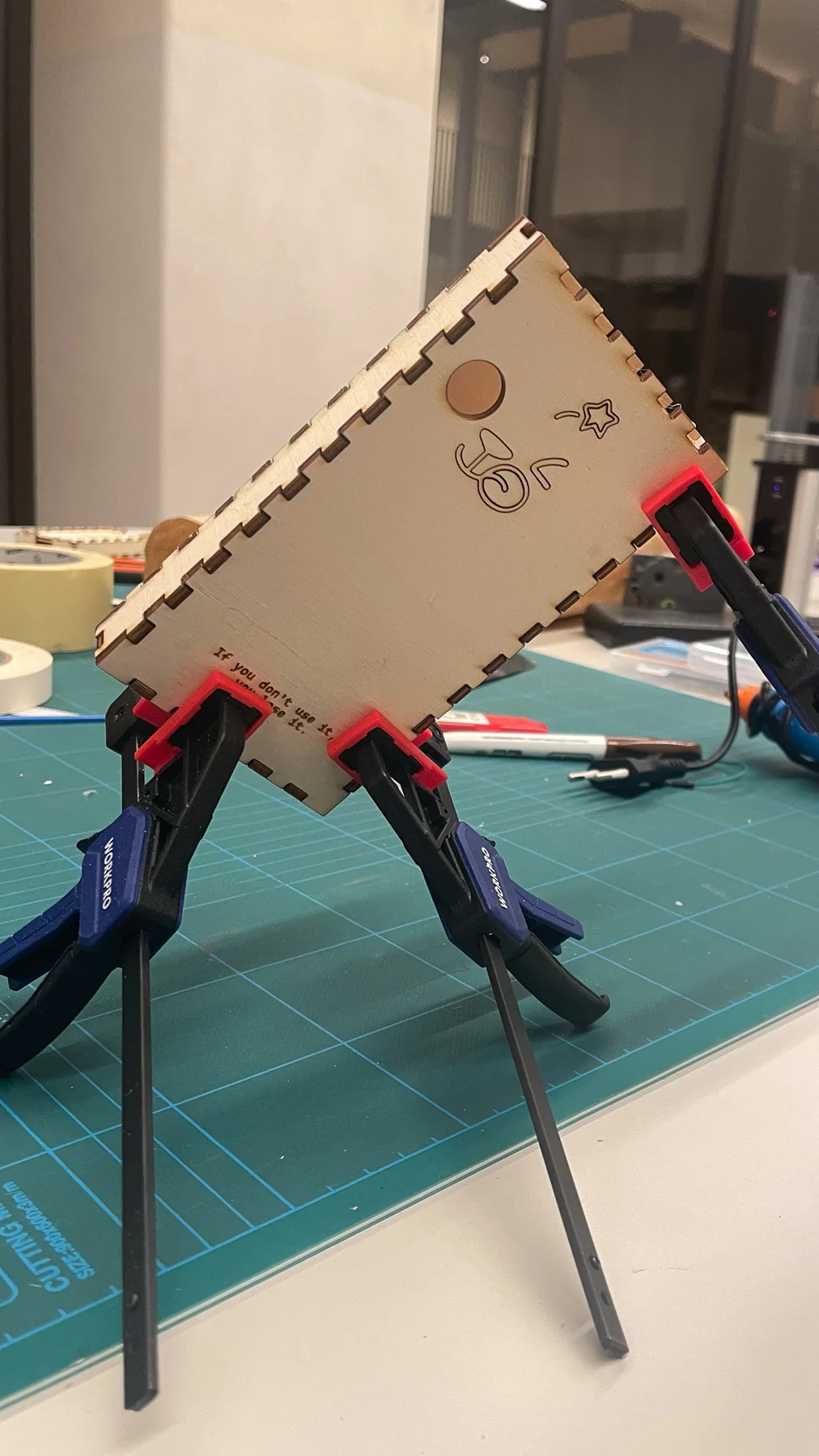 The laser-cut wooden case held in clamps while the glue sets