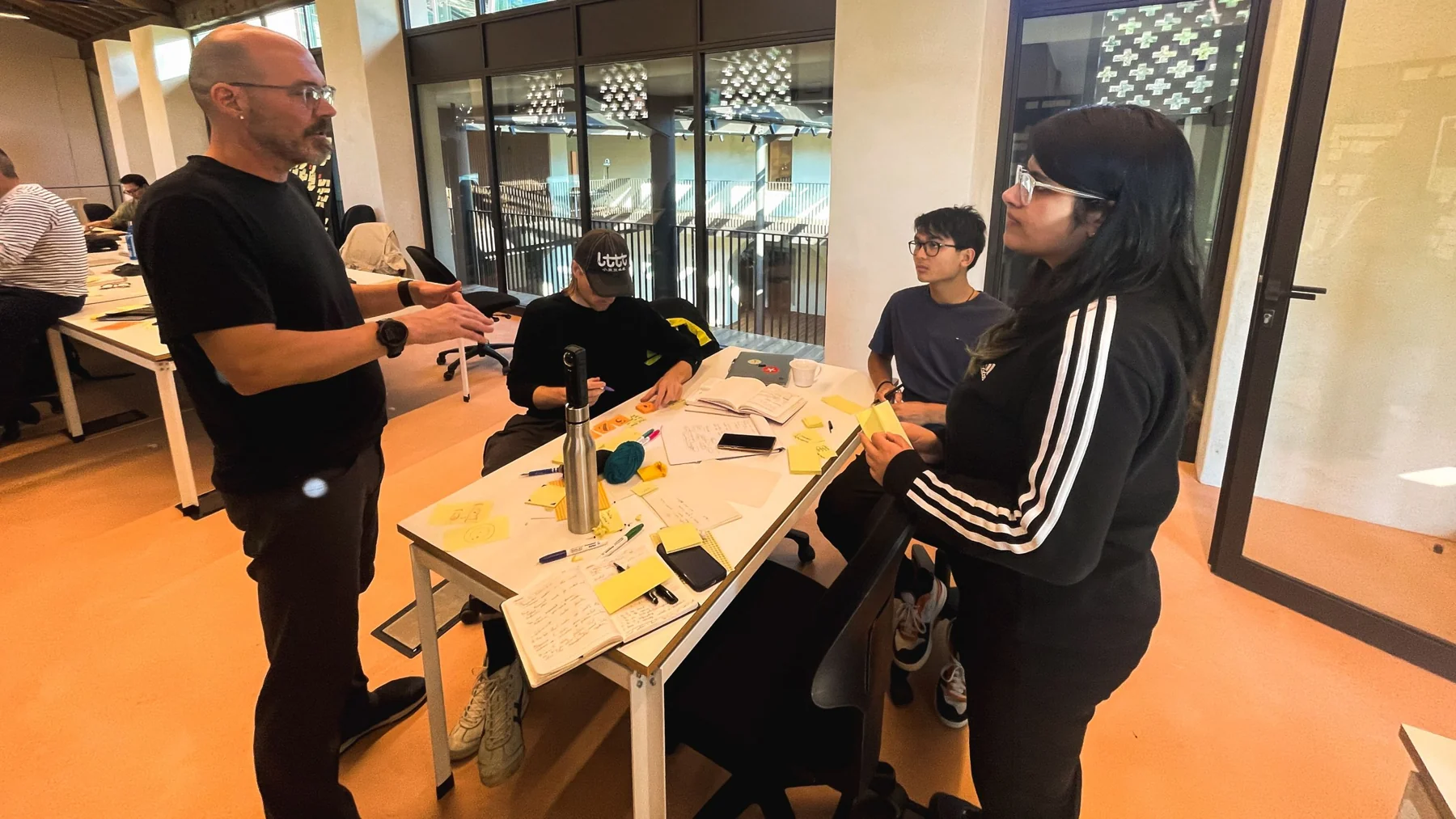 The team getting feedback from a tutor at a table covered in sticky notes
